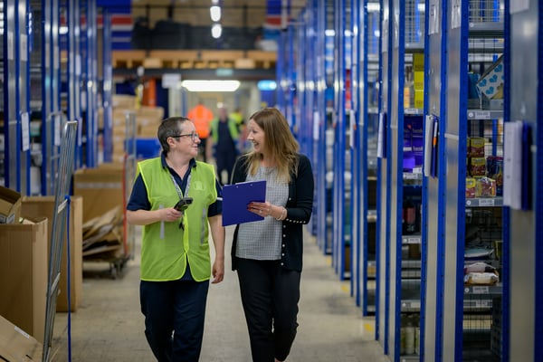 Werkgever en medewerker lopen samen door een magazijn