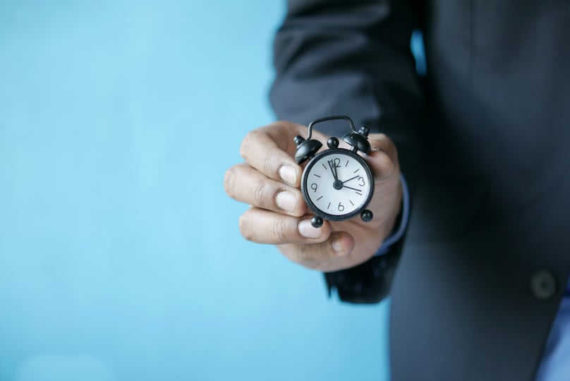 Hand die een kleine wekker vasthoudt