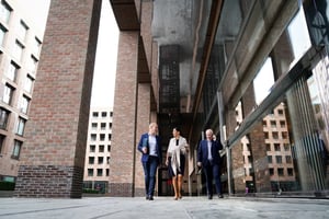 Drie mensen lopen samen voor een kantoorgebouw